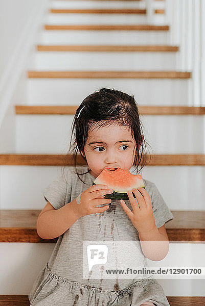 Mädchen genießt Wassermelone auf einer Treppe