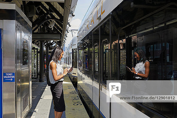 Geschäftsfrau benutzt Handy im Bahnhof
