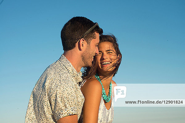 Romantisches junges Paar lacht gegen den blauen Himmel