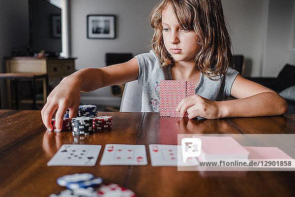 Mädchen spielen Karten am Tisch  stapeln Spielchips