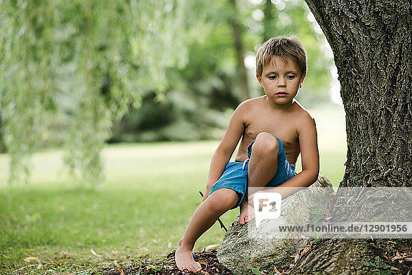 Boy daydreaming by tree trunk