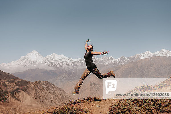 Woman jumping on peak  Annapurna Circuit  the Himalayas  Dhaulagiri and Tukuche mountains in background  Muktinath  Nepal