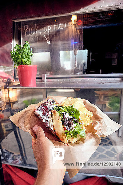Salad wrap being collected from window of food truck
