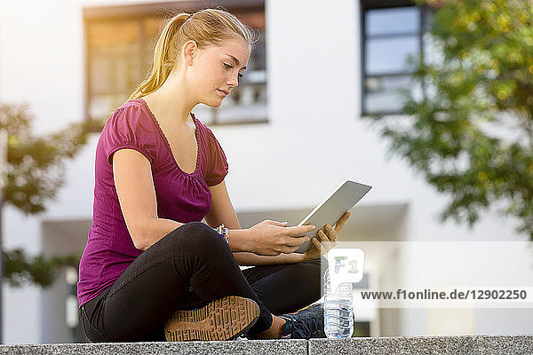 Junge Frau benutzt digitales Tablett im Park