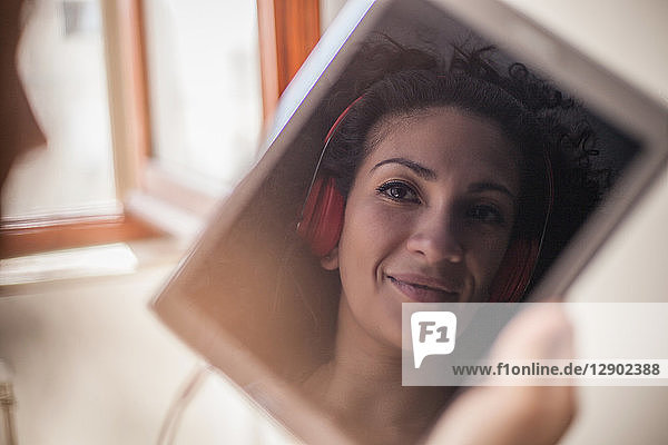 Bild eines Frauengesichts mit Kopfhörern auf digitalem Tablet