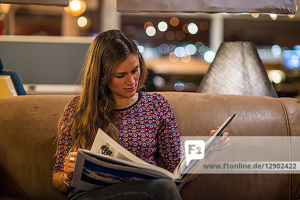 Young woman reading book in office