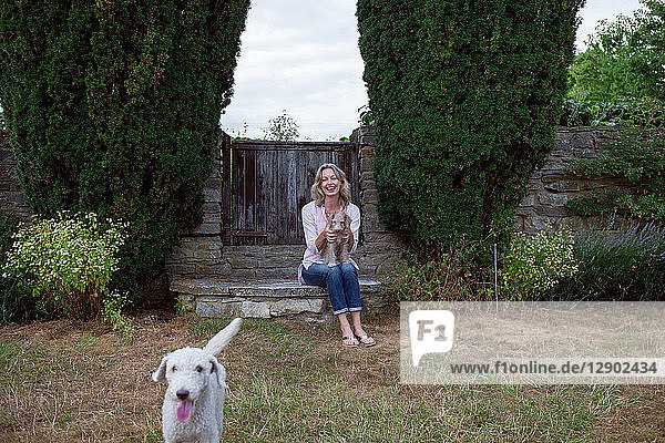 Mature woman with two dogs sitting in garden  portrait