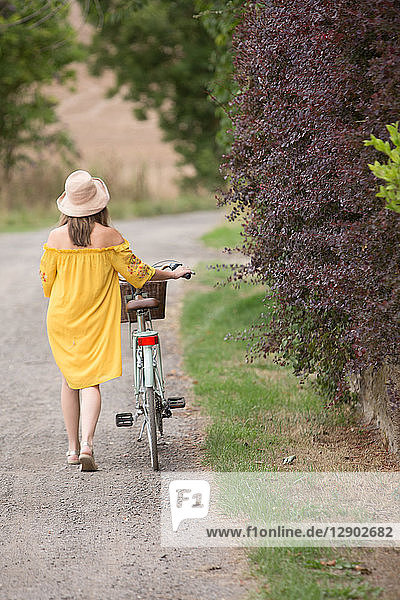 Woman walking bicycle in countryside
