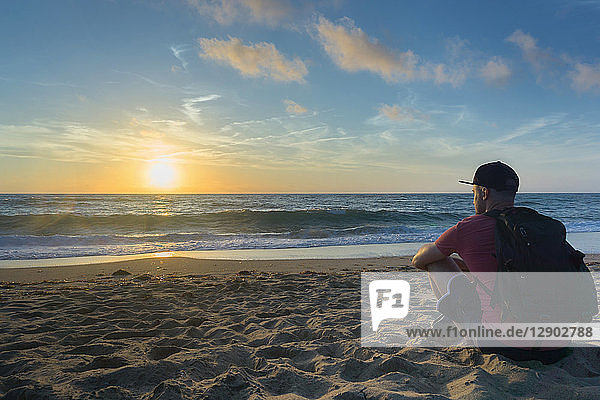 Mann genießt Sonnenuntergang am Strand