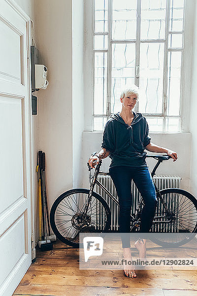 Woman sitting on bicycle at home