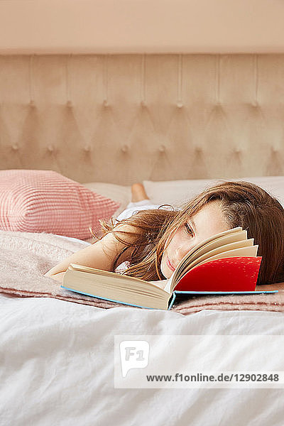 Mädchen liest Buch und träumt vor sich hin