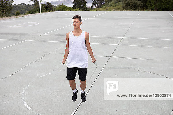 Männlicher jugendlicher Basketballspieler auf Basketballfeld überspringt