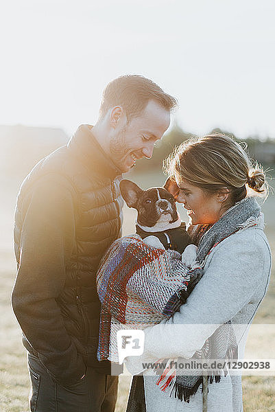 Couple carrying their puppy in woollen blanket