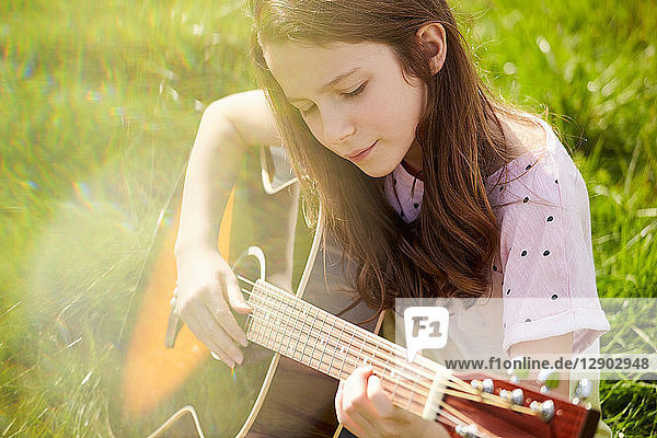 Mädchen spielt Gitarre auf Rasen