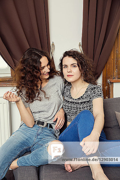 Zwei junge Freundinnen sitzen auf einem Sofa-Portrait