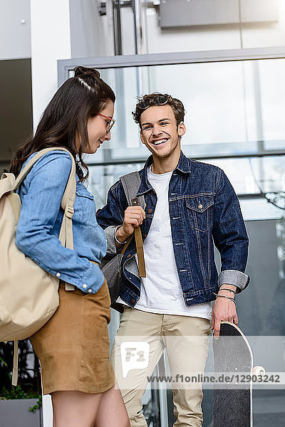 Young male and female university students laughing together in university lobby