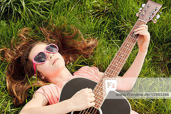 Girl playing guitar on grass