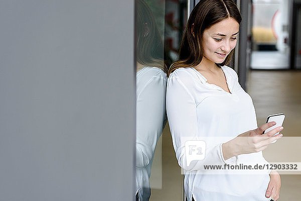 Woman leaning on glass wall using cellphone