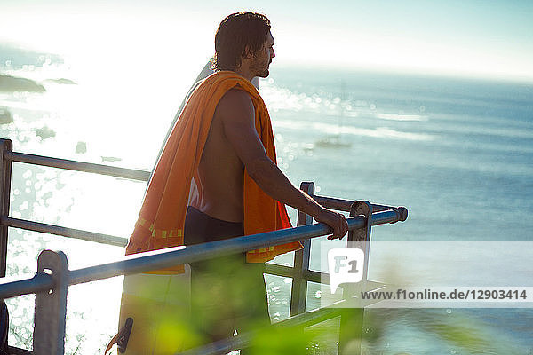 Männlicher Surfer im mittleren Erwachsenenalter  der vom Balkon auf das Meer schaut  Kapstadt  Camps Bay Beach  Kapstadt  Südafrika