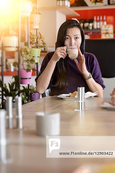 Mittlere erwachsene Frau trinkt Kaffee im Café