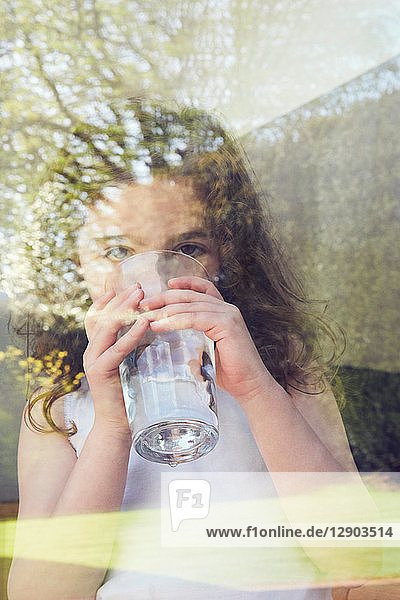 Junges Mädchen trinkt Wasser am Glasfenster