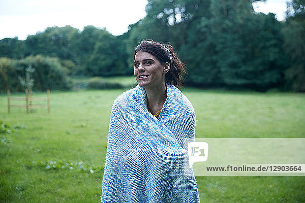 Mittelgroße erwachsene Frau im ländlichen Feld stehend  in eine Decke gehüllt  Porträt