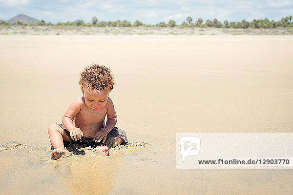 Kleinkind spielt am Strand im Sand