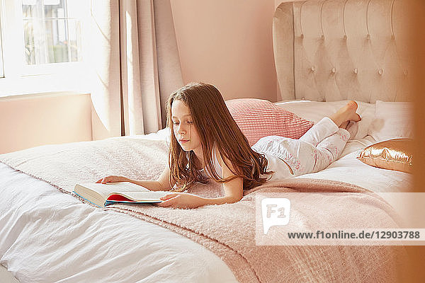 Mädchen liest Buch im Bett