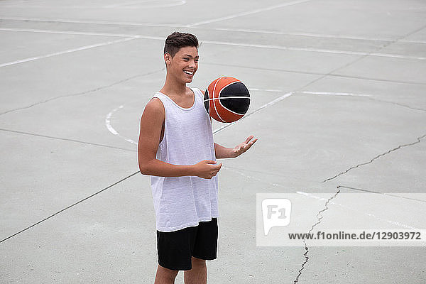 Männlicher jugendlicher Basketballspieler auf dem Basketballfeld beim Werfen und Fangen von Bällen