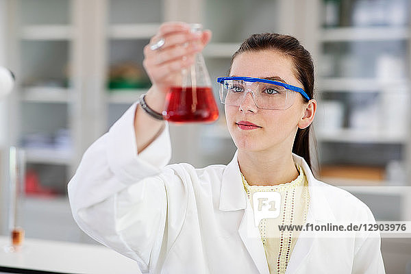 Student analysing sample in flask in laboratory