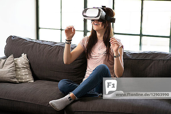 Teenager-Mädchen auf dem Sofa schaut durch ein Virtual-Reality-Headset