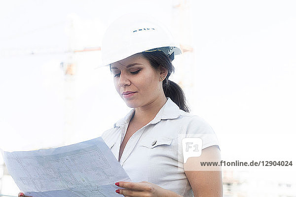 Female engineer reading blueprint