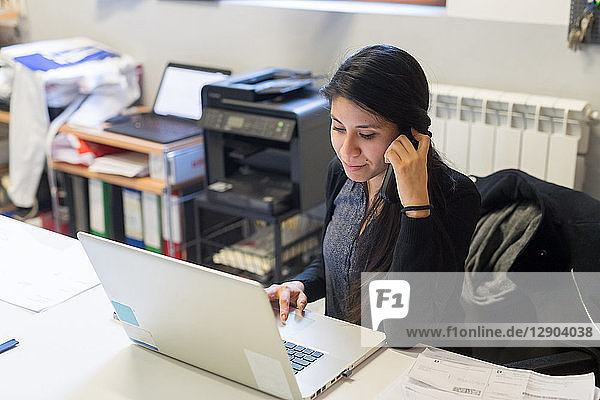 Frau benutzt Laptop und Telefon im Büro