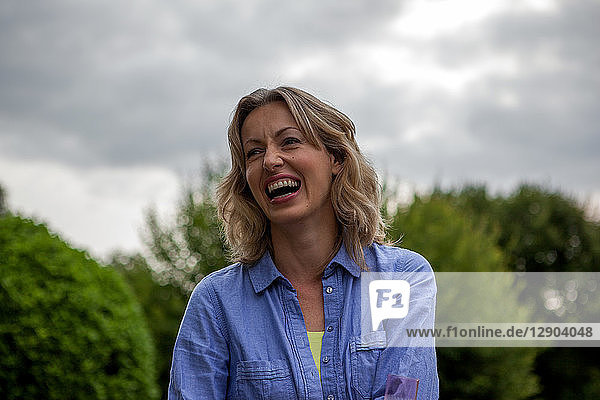 Reife Frau lacht im Garten  Kopf- und Schulterporträt