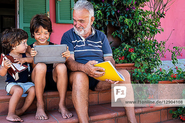 Grandfather sitting with grandsons on front door steps