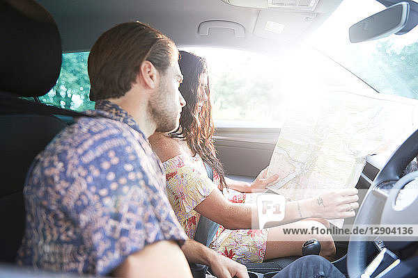 Couple sitting in car looking at folding map