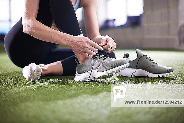 Woman tying shoelace in gym