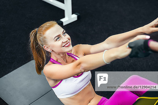 Frau macht Sit-ups im Fitnessstudio und lächelt