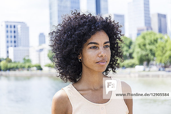 Germany  Frankfurt  portrait of young woman with curly hair in front of Main River