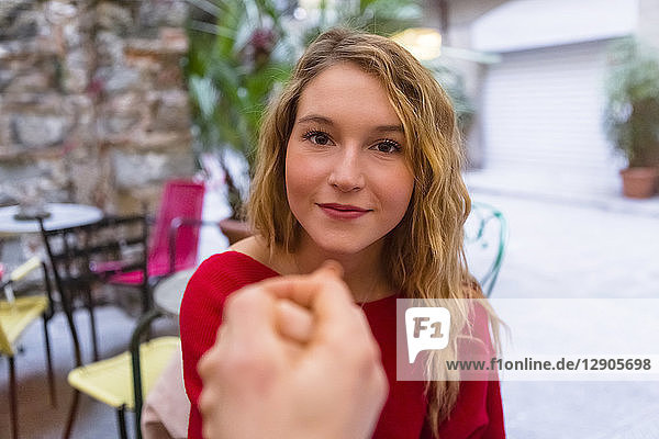 Portrait of young woman holding hands at pavement cafe