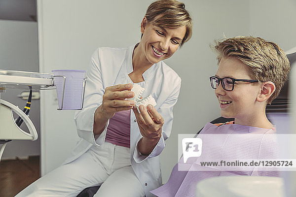 Female dentist explaining boy a tooth model