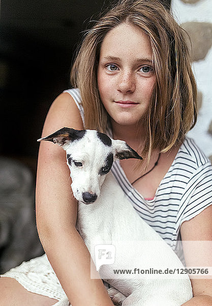 Portrait of freckled girl with puppy on her lap