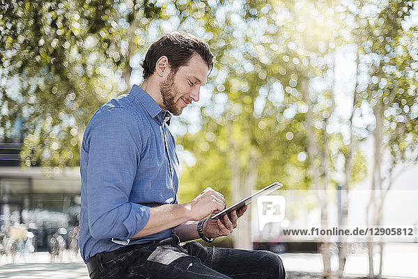 Smiling businessman using tablet outdoors in the nature