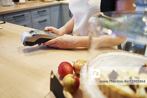 Waitress holding card reader at counter in a cafe
