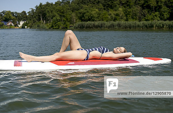 Germany  Brandenburg  young woman relaxing on paddleboard on Zeuthener See