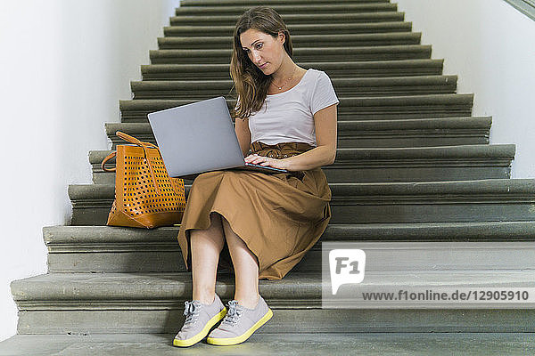 Woman sitting on a staircase using laptop