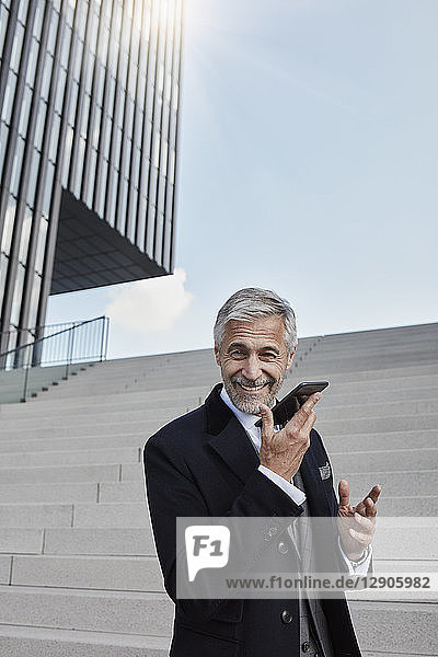 Portrait of content businessman on the phone standing in front of stairs