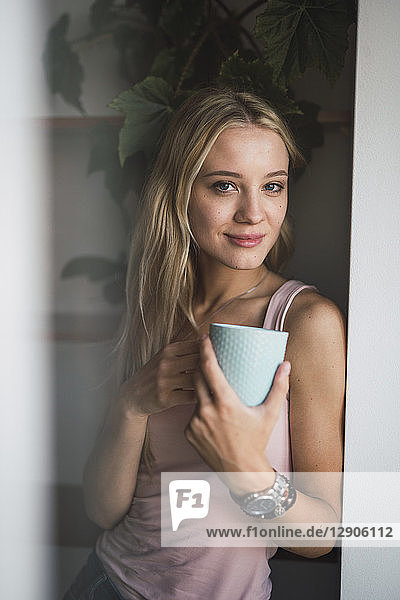 Portrait of smiling blond young woman holding coffee mug