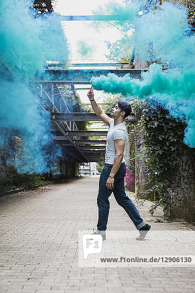 Young man walking with smoke torch outdoors