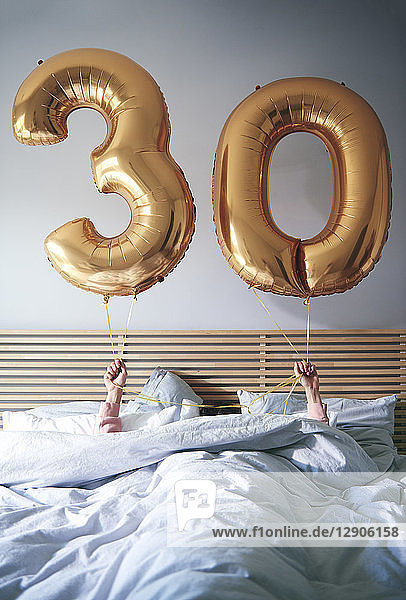 Woman with golden balloons celebrating her birthday in bed